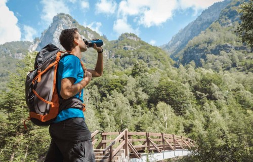 Trekking Through Green Hills with Refreshing Water Break